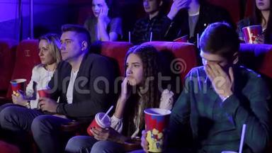 一群<strong>年轻</strong>人<strong>在</strong>电影院看一部悲伤的电影，女孩<strong>在哭</strong>。